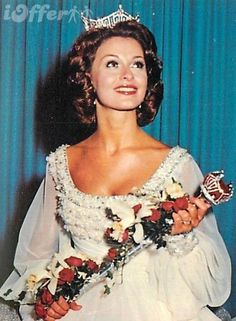 an old photo of a woman wearing a tiara and holding a flower in her hand