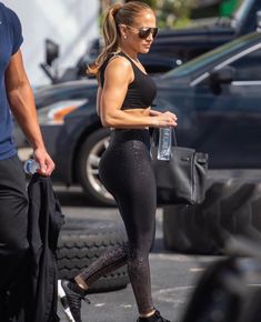 a woman in black sports bra and leggings walking down the street