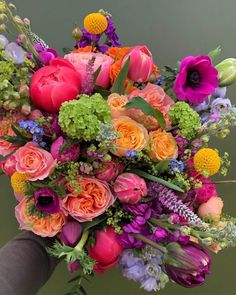 a person holding a bouquet of flowers in their hand with the background green and purple