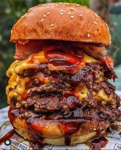 a cheeseburger with bacon and barbecue sauce on it's bun is sitting on top of a newspaper