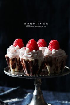 small cupcakes with chocolate frosting and raspberries are on a cake plate