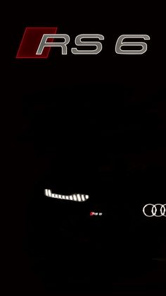 the front end of a car with its lights on in the dark, and an rs 6 logo behind it