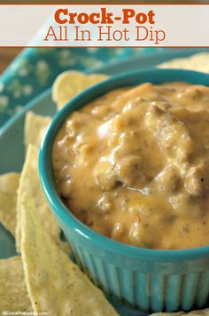 a blue bowl filled with dip and tortilla chips on top of a plate