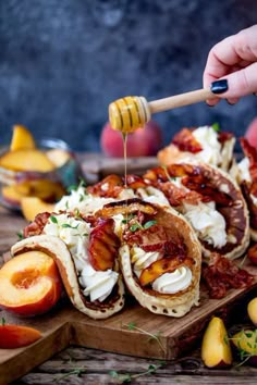 a person drizzling honey onto some food on a cutting board with peaches