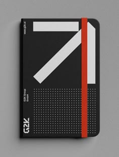 a black and red notebook with white lines on the cover, sitting on a gray surface