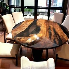 a dining table with chairs around it in front of a large window overlooking the city