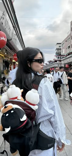 a woman is walking down the street with stuffed animals on her back