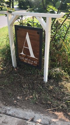 a sign that is on the side of a road in front of some grass and bushes