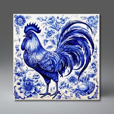 a blue and white tile with a rooster on it's side, surrounded by flowers