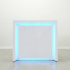 a white box with blue lights on the sides in an empty room or studio space