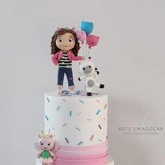 a white cake with pink and blue icing, an animal figurine on top