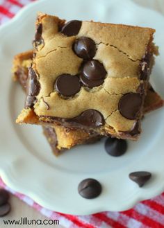 two pieces of chocolate chip cookie cake on a white plate with chocolate chips around it