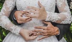 the bride and groom are holding each other's hands while they hold their wedding rings