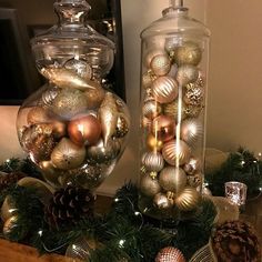 two glass vases filled with ornaments on top of a table