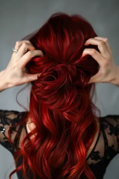 a woman with red hair is holding her hands up to her head and looking at the camera