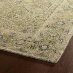 a beige rug with blue and green designs on the top is laying on a wooden floor