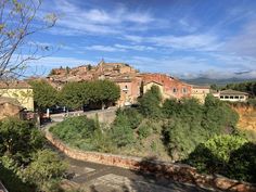 a small village on top of a hill in the middle of trees and buildings below