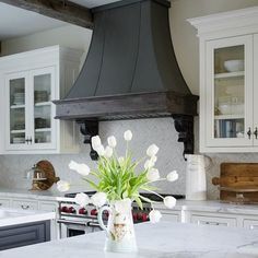 a vase with white flowers sitting on top of a kitchen counter next to an oven