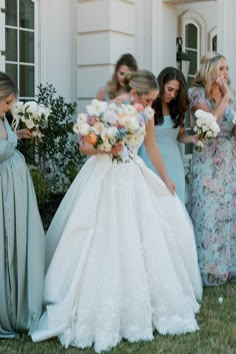 a bride and her bridesmaids are standing in front of a house with their bouquets