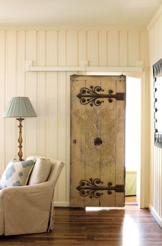 a living room with a couch and chair in front of a wooden door that has an ornate design on it