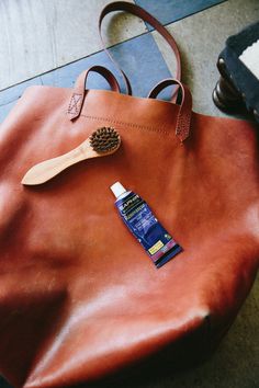 a brown leather bag with a wooden brush and tube of toothpaste on it