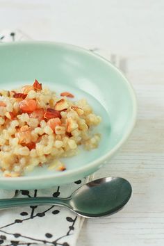 a bowl filled with food sitting on top of a table next to a spoon and napkin