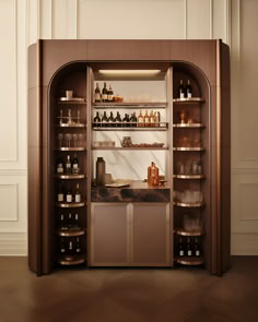 an open display case with bottles and glasses on it's shelves in a white walled room