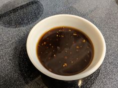 a white bowl filled with sauce sitting on top of a counter