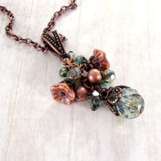 "A dainty cluster of Czech glass beads in shades of soft, subdued green and dusty pink. I adorned the larger beads and flowers with exquisitely detailed antiqued copper filigree to enhance the Old-World feel. The pendant hangs from antiqued genuine copper and features an adjustable lobster claw closure. --------------------------------------------------------------------------------------------- Dimensions and details: - Drop of the pendant (from top of the bail to bottom of bead drop) measures Nature Rose, Czech Glass Jewelry, Pink Nature, Bijoux Fil Aluminium, Mixed Media Jewelry, Nature Necklace, Repurposed Jewelry, Assemblage Jewelry, Long Necklaces