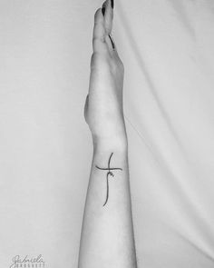 a person's foot with a small cross tattoo on the left side of their arm