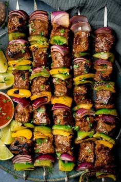 several skewers filled with meat and veggies next to dipping sauces