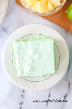 a piece of cake sitting on top of a white plate next to a bowl of fruit