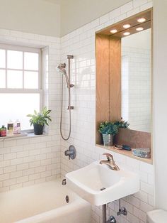 a bath room with a toilet a sink and a tub next to a window in it