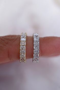 a woman's hand holding two diamond hoop earrings