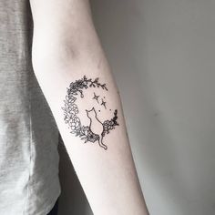 a woman's arm with a tattoo on it that has an image of a cat and stars