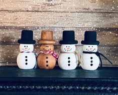 three snowmen are standing next to each other in front of a wooden wall with snow flakes on it