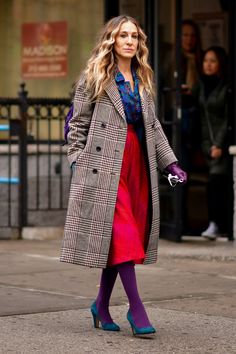 a woman walking down the street wearing purple tights and a plaid coat with her hands in her pockets