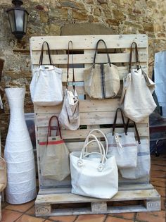 several purses and handbags are displayed on a pallet in front of a stone wall