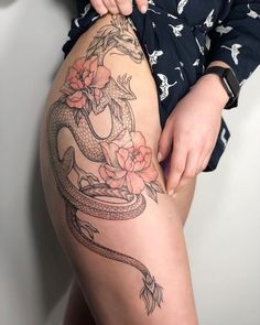 a woman with a dragon tattoo on her thigh holding onto the side of her leg