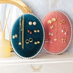 three different colored jewelry bags sitting on top of a white shelf next to a mirror