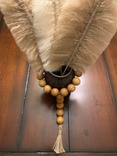 a wooden bead and tassel decoration on a wood floor next to a lamp