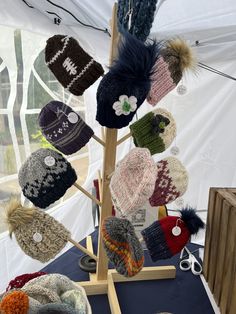 many hats are hanging on a wooden stand in front of a white tent with blue tarp