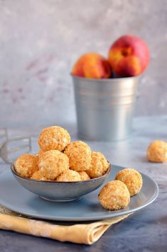 a bowl filled with donuts next to some peaches on a plate and napkin