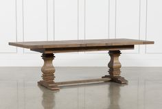 a wooden table sitting on top of a floor next to a white wall with wood trimming