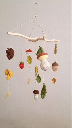 a crocheted mobile with fruits and nuts hanging from it's sides on a white wall