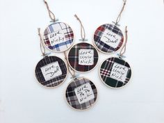 four plaid fabric ornament hanging from twine with handwritten words on them