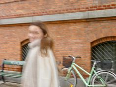 a blurry photo of a woman walking down the street next to a green bike