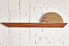 a wooden shelf with two birds on it against a white brick wall in the shape of an oval