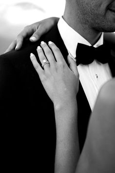 a man in a tuxedo adjusting the collar of a woman's dress