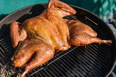 a chicken is cooking on the grill with it's wings still attached to it